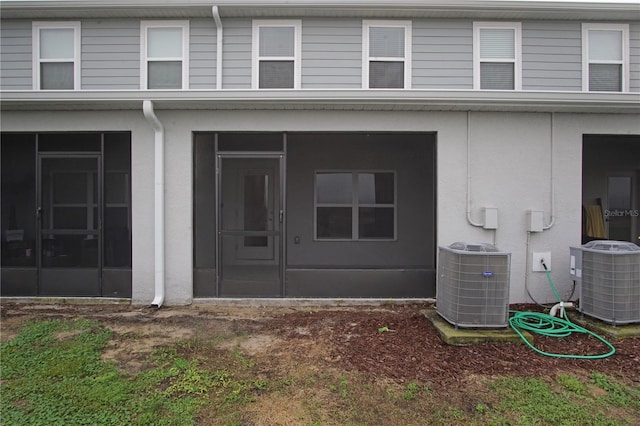 rear view of property featuring a sunroom and central AC unit