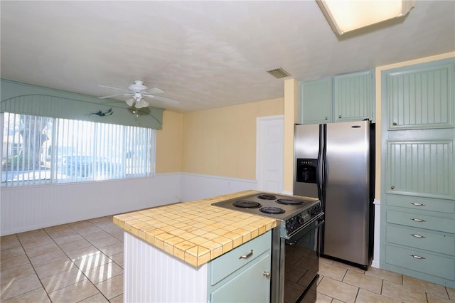 kitchen with stainless steel refrigerator with ice dispenser, tile countertops, light tile patterned floors, visible vents, and electric range