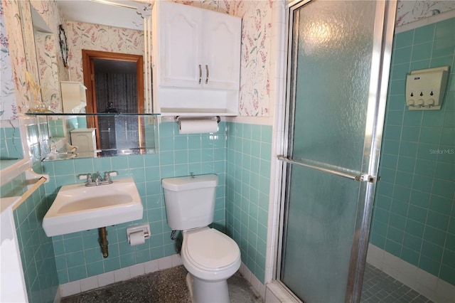 bathroom featuring a sink, tile walls, wainscoting, a stall shower, and wallpapered walls