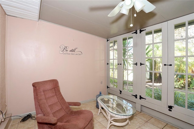 living area featuring a ceiling fan, baseboards, and light tile patterned floors