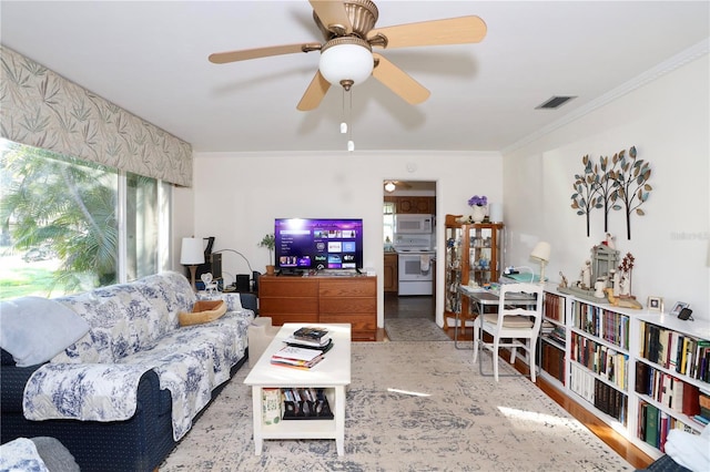 living room with ornamental molding, visible vents, and ceiling fan