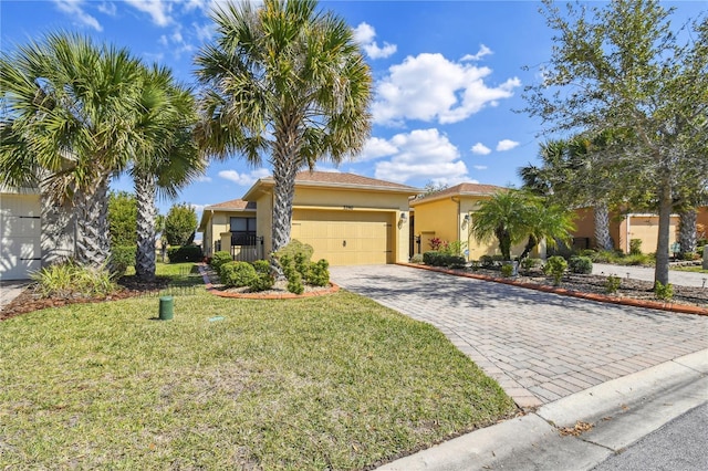 view of front facade with a garage, decorative driveway, a front yard, and stucco siding