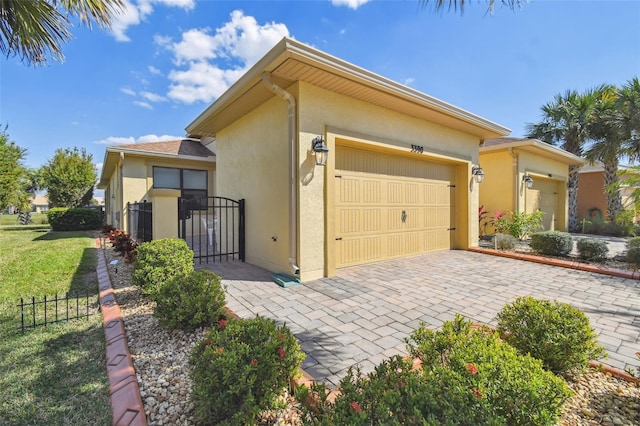 3390 Fallbrook Dr, Kissimmee, FL 34759 - view of front of home featuring a garage, a gate, fence, decorative driveway, and stucco siding