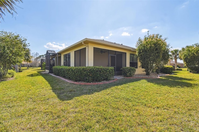 3390 Fallbrook Dr, Kissimmee, FL 34759 - view of side of property with glass enclosure, a ceiling fan, a lawn, and stucco siding