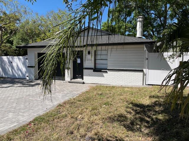 view of front of home featuring a front yard, a gate, decorative driveway, and brick siding