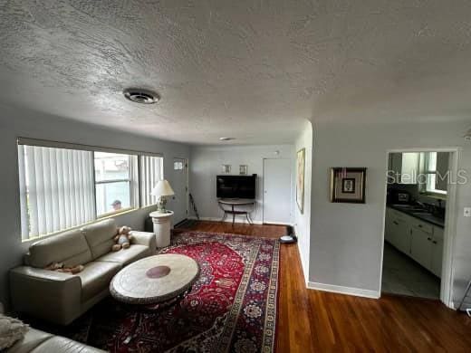 living area featuring a textured ceiling, dark wood-type flooring, and visible vents