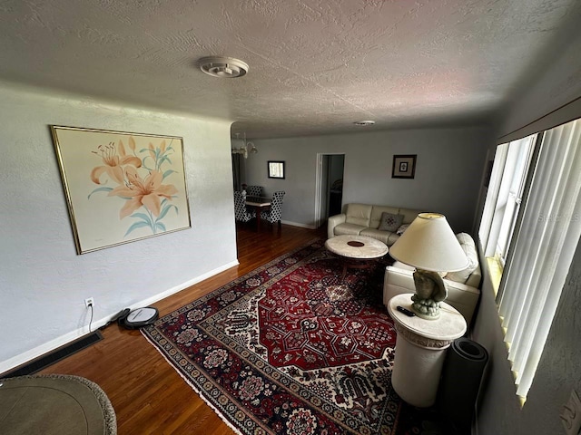 living area featuring a textured ceiling, baseboards, and wood finished floors