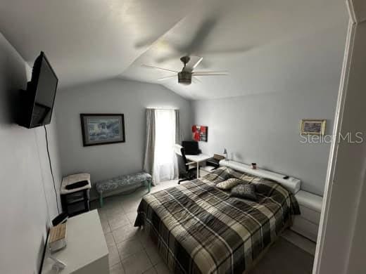 tiled bedroom featuring a ceiling fan and lofted ceiling