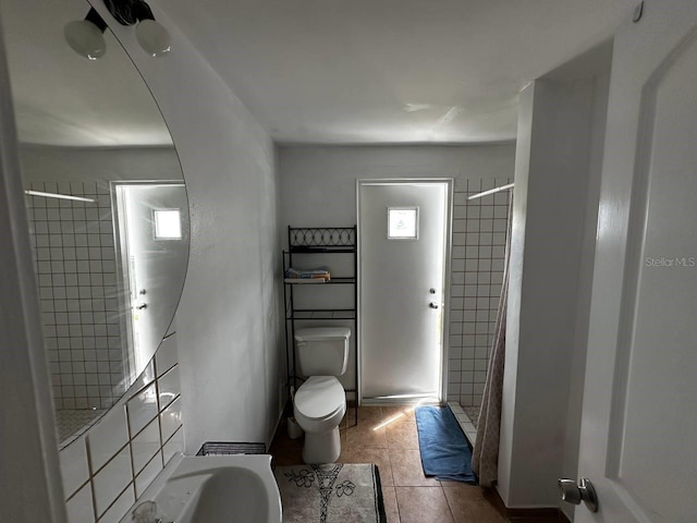 bathroom with curtained shower, toilet, and tile patterned floors