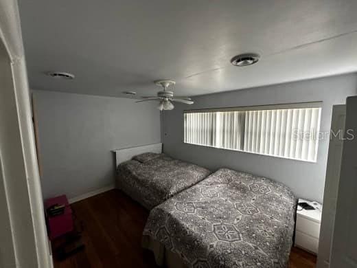 bedroom featuring dark wood-style floors, ceiling fan, visible vents, and baseboards