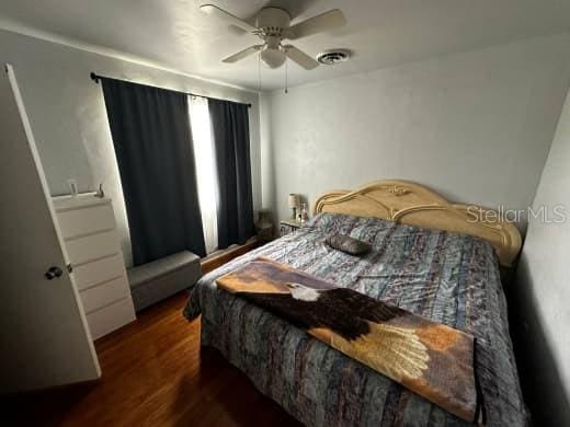 bedroom featuring dark wood-style floors, visible vents, and a ceiling fan