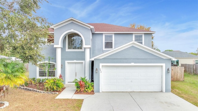 traditional home featuring a front yard, driveway, fence, and stucco siding