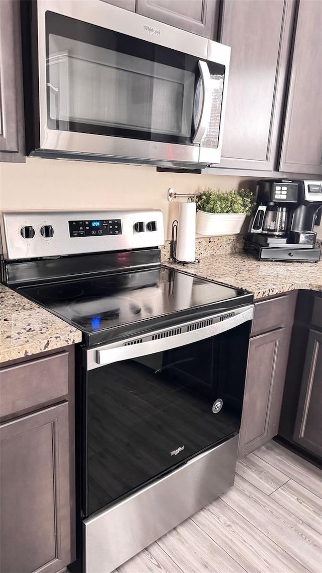 kitchen featuring dark brown cabinets, appliances with stainless steel finishes, and light stone countertops