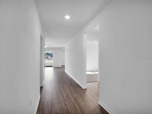 hall with baseboards, dark wood-type flooring, and a textured wall