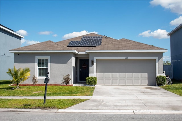 single story home with stucco siding, a front yard, roof mounted solar panels, a garage, and driveway