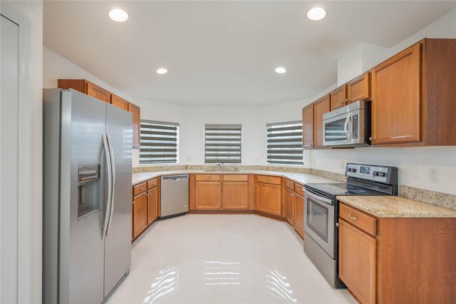 kitchen with appliances with stainless steel finishes, brown cabinets, a sink, and recessed lighting