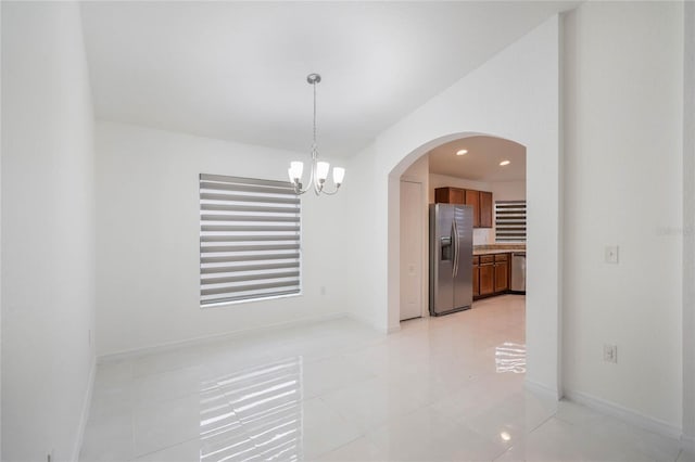 unfurnished dining area with baseboards, arched walkways, a notable chandelier, and recessed lighting