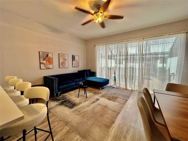 living area with a ceiling fan and wood finished floors