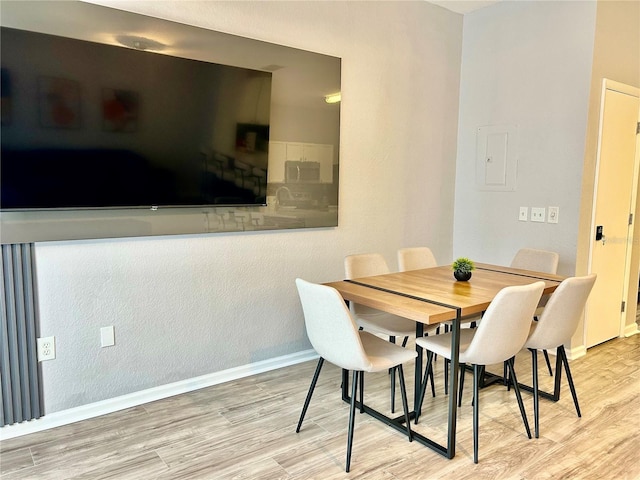 dining room with electric panel, baseboards, and wood finished floors