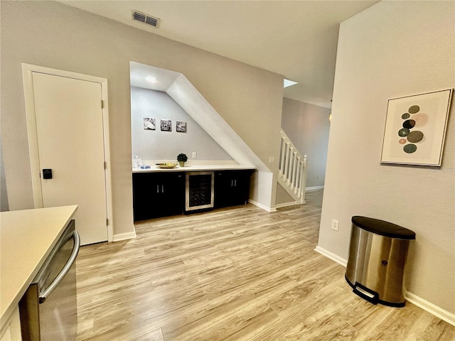 bar with wine cooler, visible vents, baseboards, stairway, and light wood-type flooring