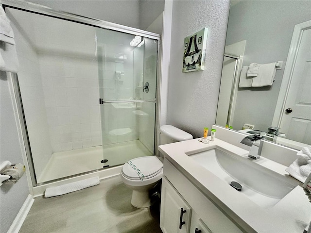 bathroom with vanity, a shower stall, toilet, and wood finished floors