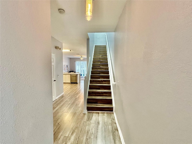 staircase featuring baseboards and wood finished floors