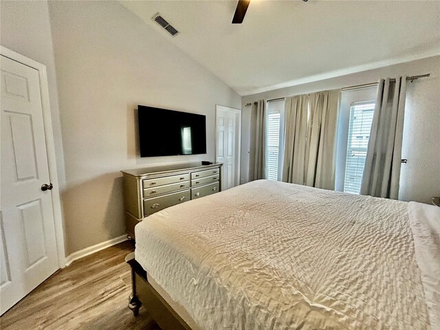 bedroom featuring wood finished floors, a ceiling fan, visible vents, vaulted ceiling, and baseboards