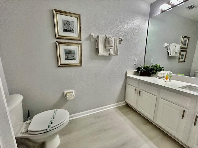 bathroom featuring baseboards, visible vents, toilet, and wood finished floors