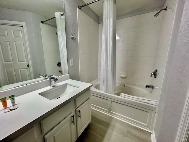 full bathroom featuring a textured wall, shower / bathtub combination with curtain, vanity, and wood finished floors