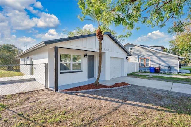 view of side of property featuring board and batten siding, driveway, an attached garage, and fence