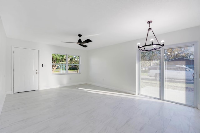 unfurnished room with ceiling fan with notable chandelier and baseboards