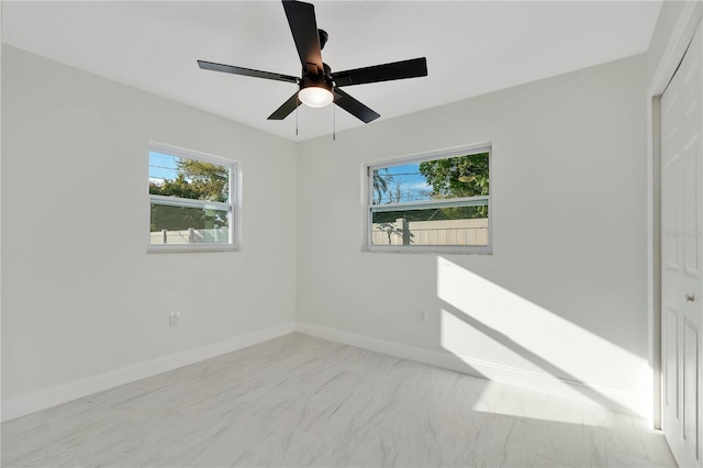 spare room featuring ceiling fan and baseboards