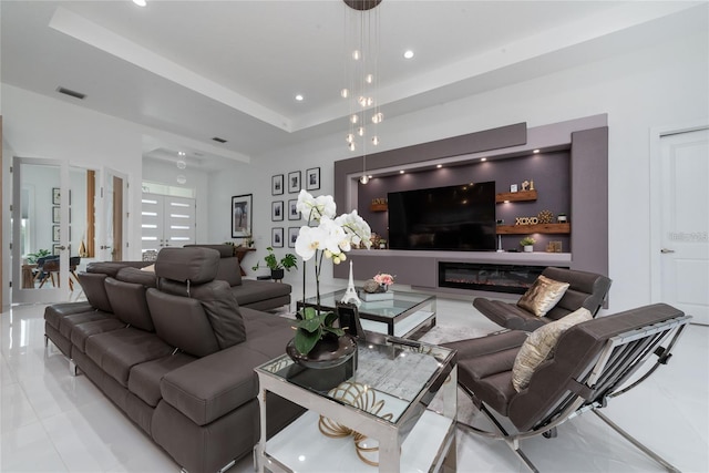 living room with visible vents, a glass covered fireplace, marble finish floor, a tray ceiling, and recessed lighting