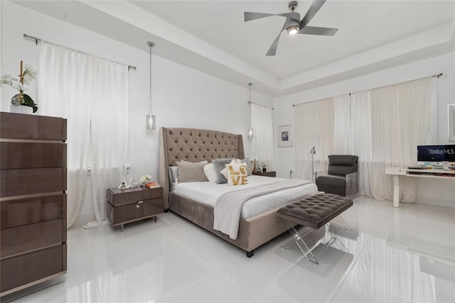 bedroom featuring ceiling fan, a tray ceiling, and light tile patterned flooring