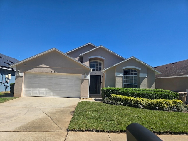 single story home featuring a front lawn, driveway, an attached garage, and stucco siding