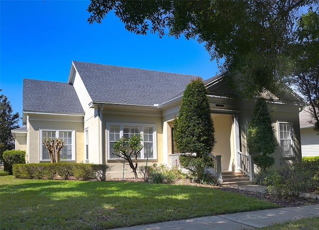 view of front of home with a front lawn, roof with shingles, and stucco siding