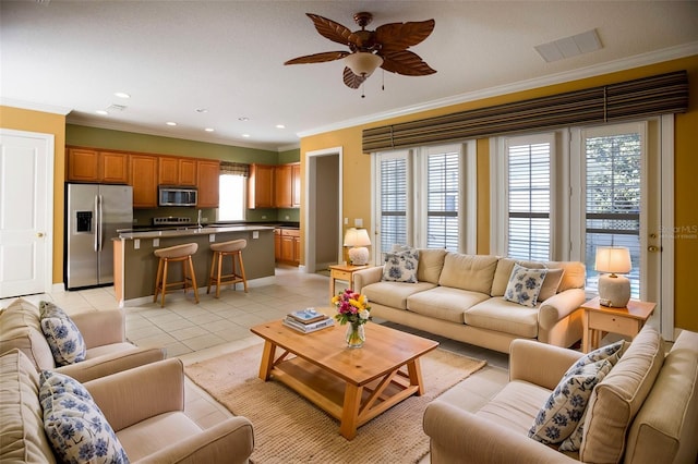 living area featuring light tile patterned floors, visible vents, ornamental molding, and a ceiling fan