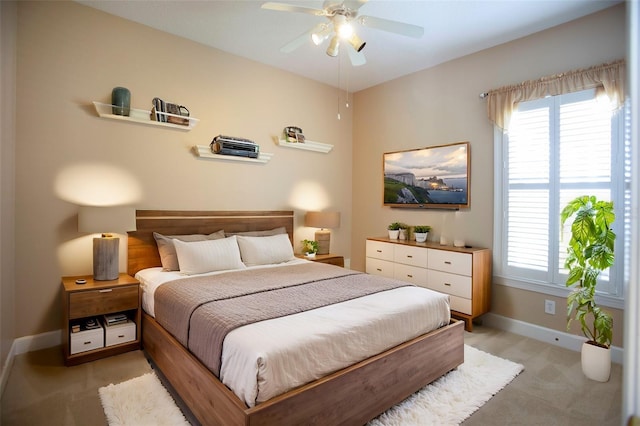 bedroom featuring multiple windows, light colored carpet, baseboards, and ceiling fan