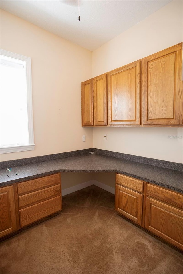 unfurnished office with built in desk and dark colored carpet