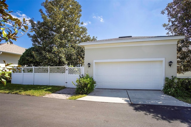 garage with a gate, fence, and driveway