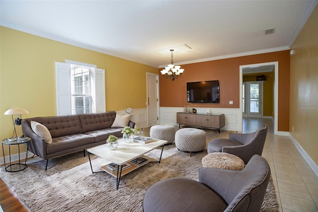 living room featuring visible vents, a wainscoted wall, light tile patterned flooring, crown molding, and a chandelier