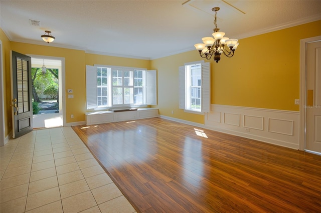 interior space with a notable chandelier, light wood-style flooring, and crown molding