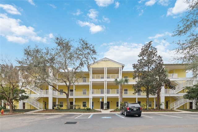 view of property featuring stairs and uncovered parking