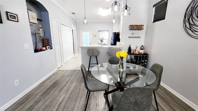 dining room featuring visible vents, crown molding, baseboards, and wood finished floors