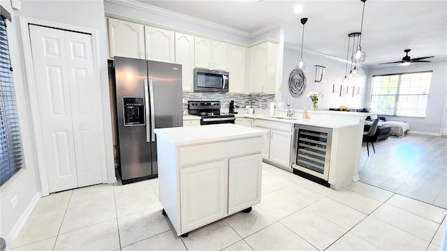 kitchen with wine cooler, appliances with stainless steel finishes, ornamental molding, a peninsula, and backsplash