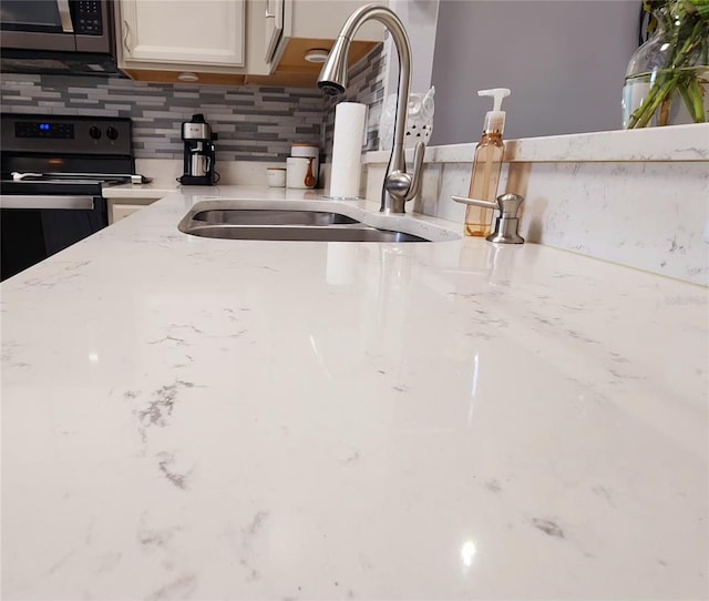 interior details featuring black electric range, tasteful backsplash, stainless steel microwave, and light stone countertops