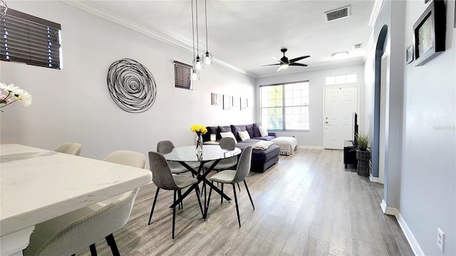 dining room with visible vents, ornamental molding, a ceiling fan, light wood-type flooring, and baseboards