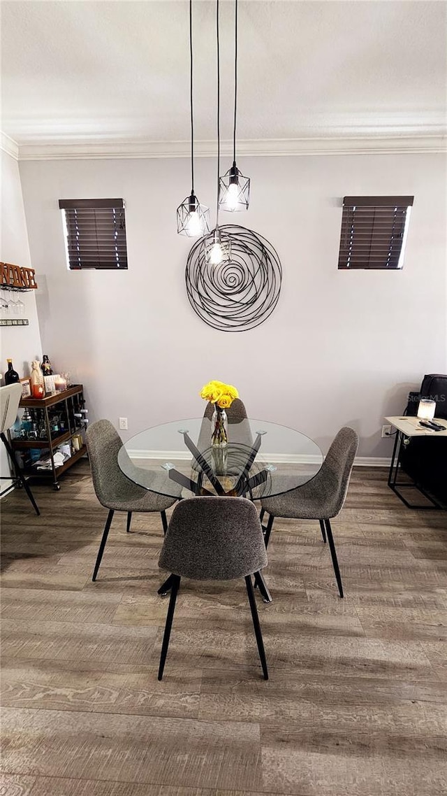 dining area featuring baseboards, crown molding, and wood finished floors