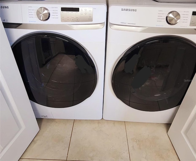 laundry area with laundry area, washer and clothes dryer, and tile patterned floors