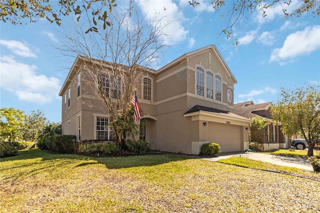 traditional-style house with a garage, a front yard, concrete driveway, and stucco siding